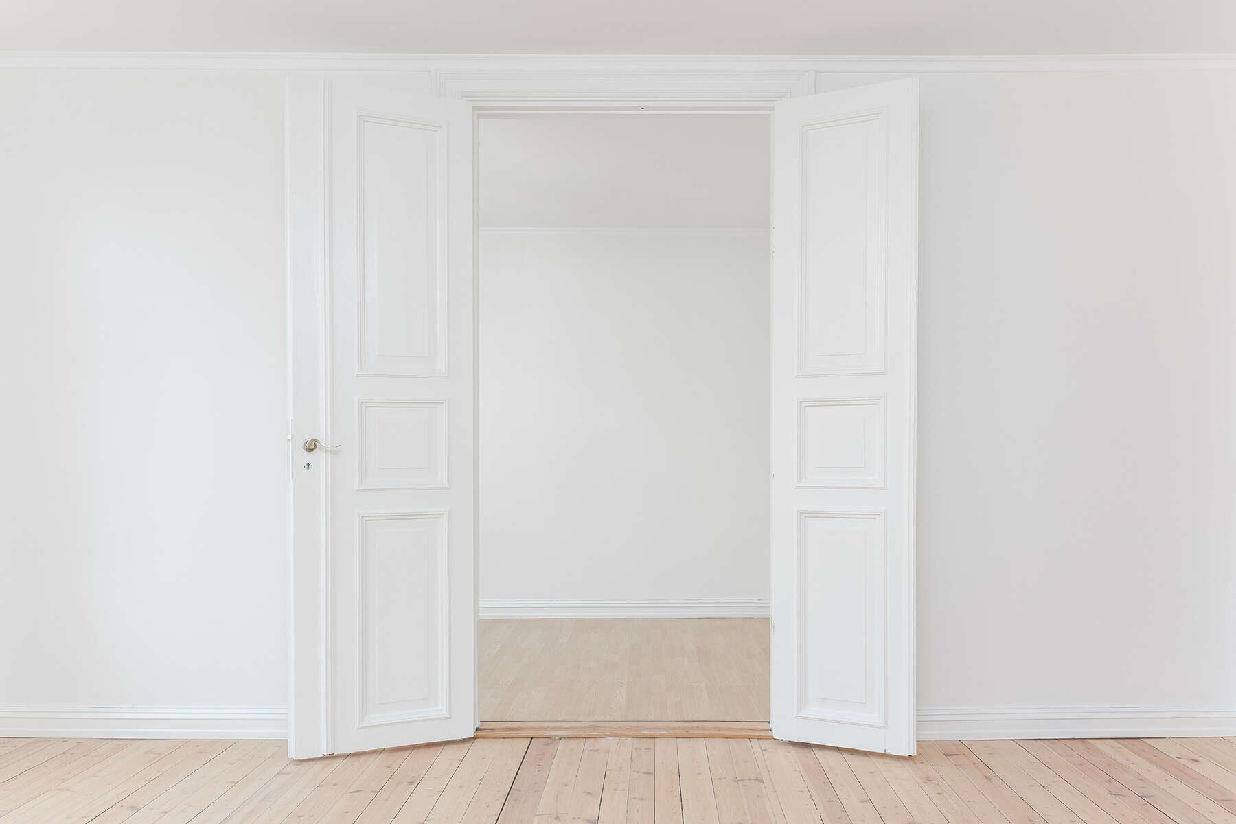 A white room with two doors open to the living room.